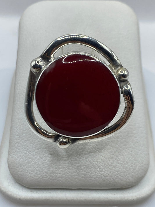 Anillo de plata ajustable con coral rojo natural en el dedo de una mujer