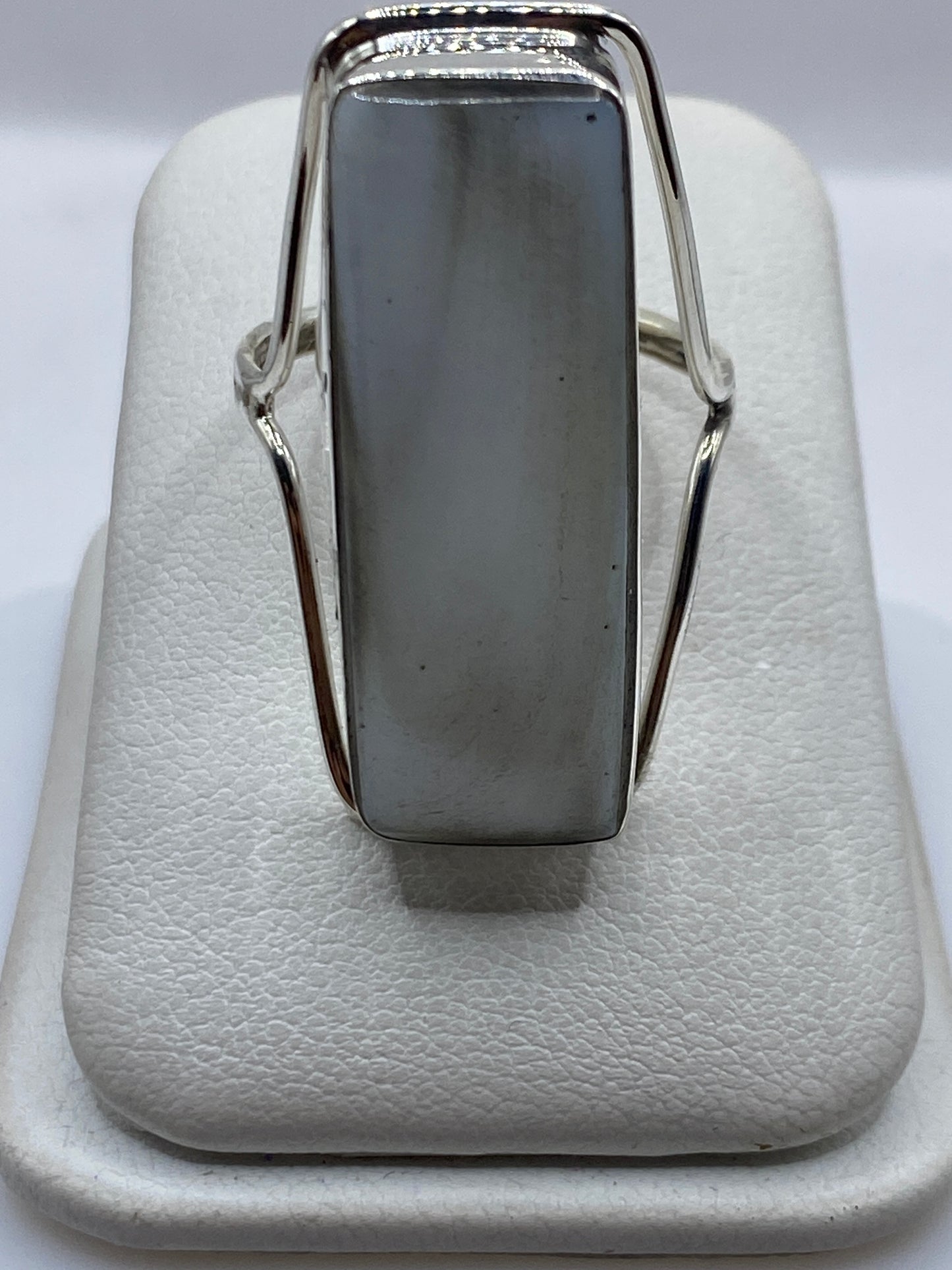 Anillo de plata solitario con piedra blanca brillante en la mano de una mujer