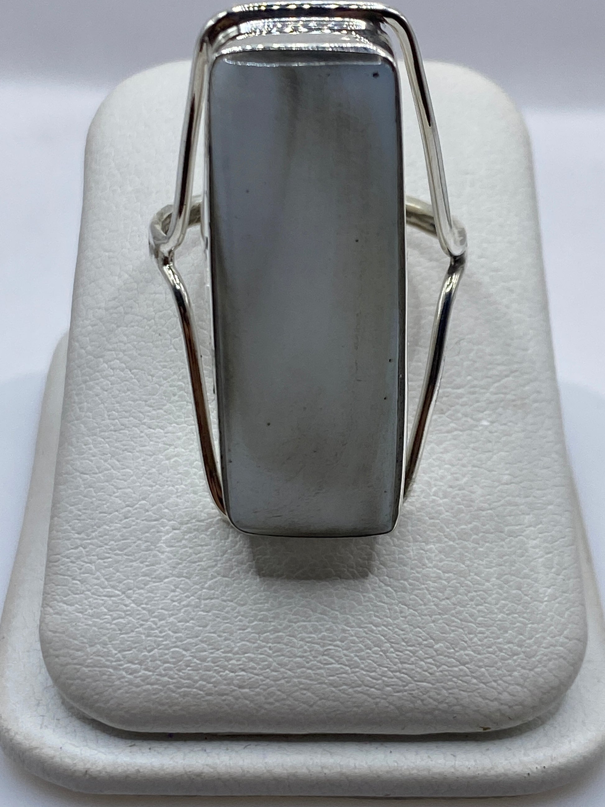 Anillo de plata solitario con piedra blanca brillante en la mano de una mujer