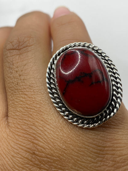 Anillo de coral sobre fondo gris mostrando el sello 925 MEXICO en la banda