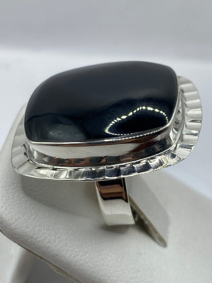 Anillo solitario de ónix en plata en la mano de una mujer mostrando el brillo natural