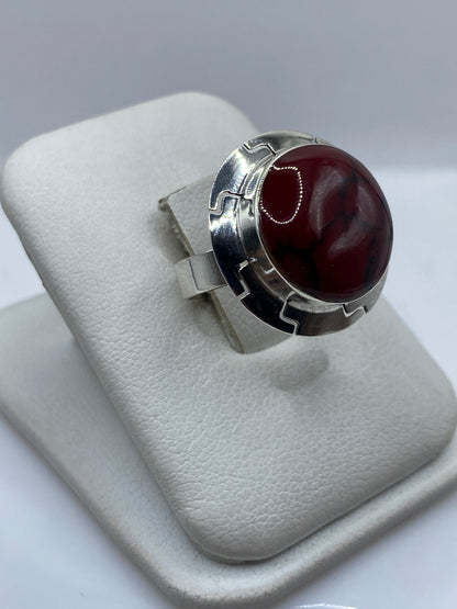 Anillo de plata .925 con coral rojo engastado, vista frontal sobre dedos