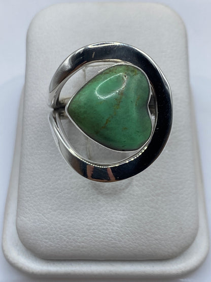 Anillo de plata con malaquita verde en forma de corazón, vista frontal en dedo