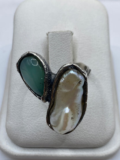Anillo de plata con perla natural blanca en marco geométrico, vista de frente sobre mano