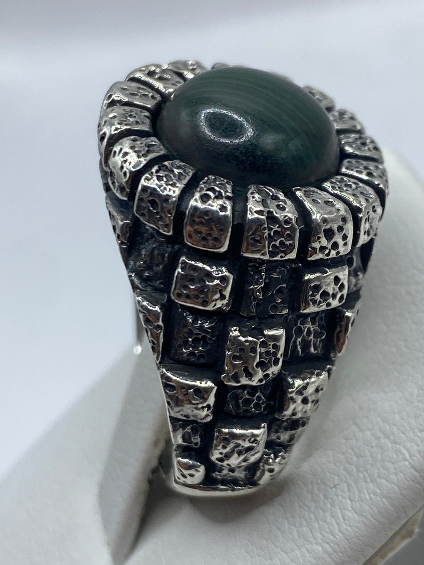 Anillo malaquita verde en mano de hombre, mostrando presencia y peso