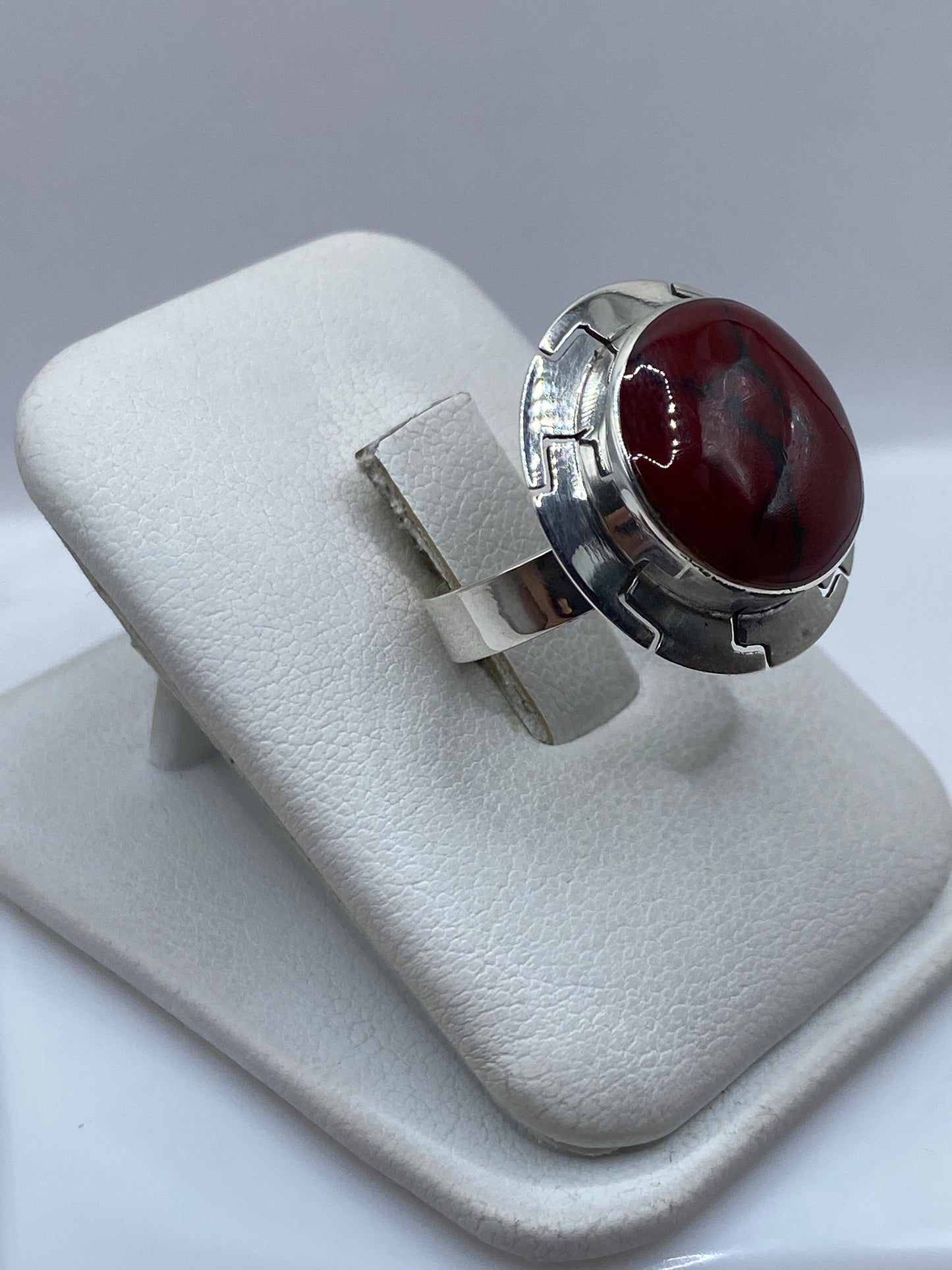 Anillo ajustable de coral rojo en la mano de una mujer, mostrando el brillo natural de la piedra