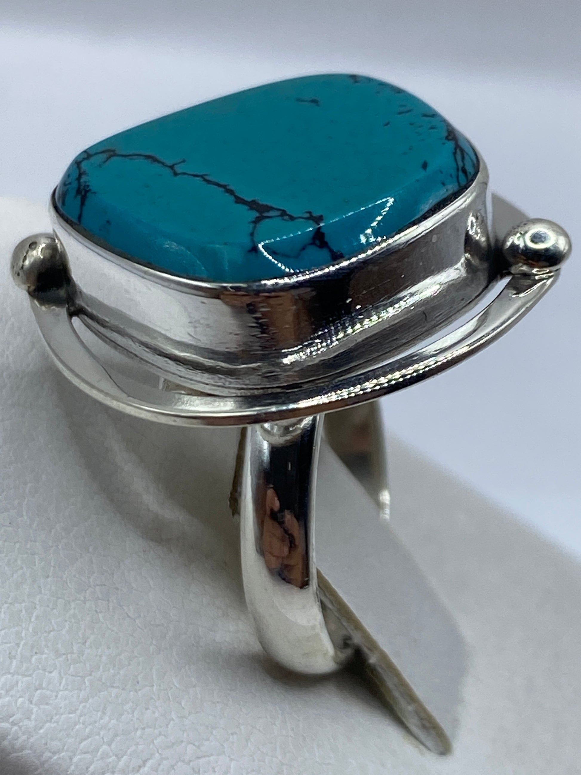 Anillo turquesa puesto en mano de mujer, vetas negras visibles en piedra