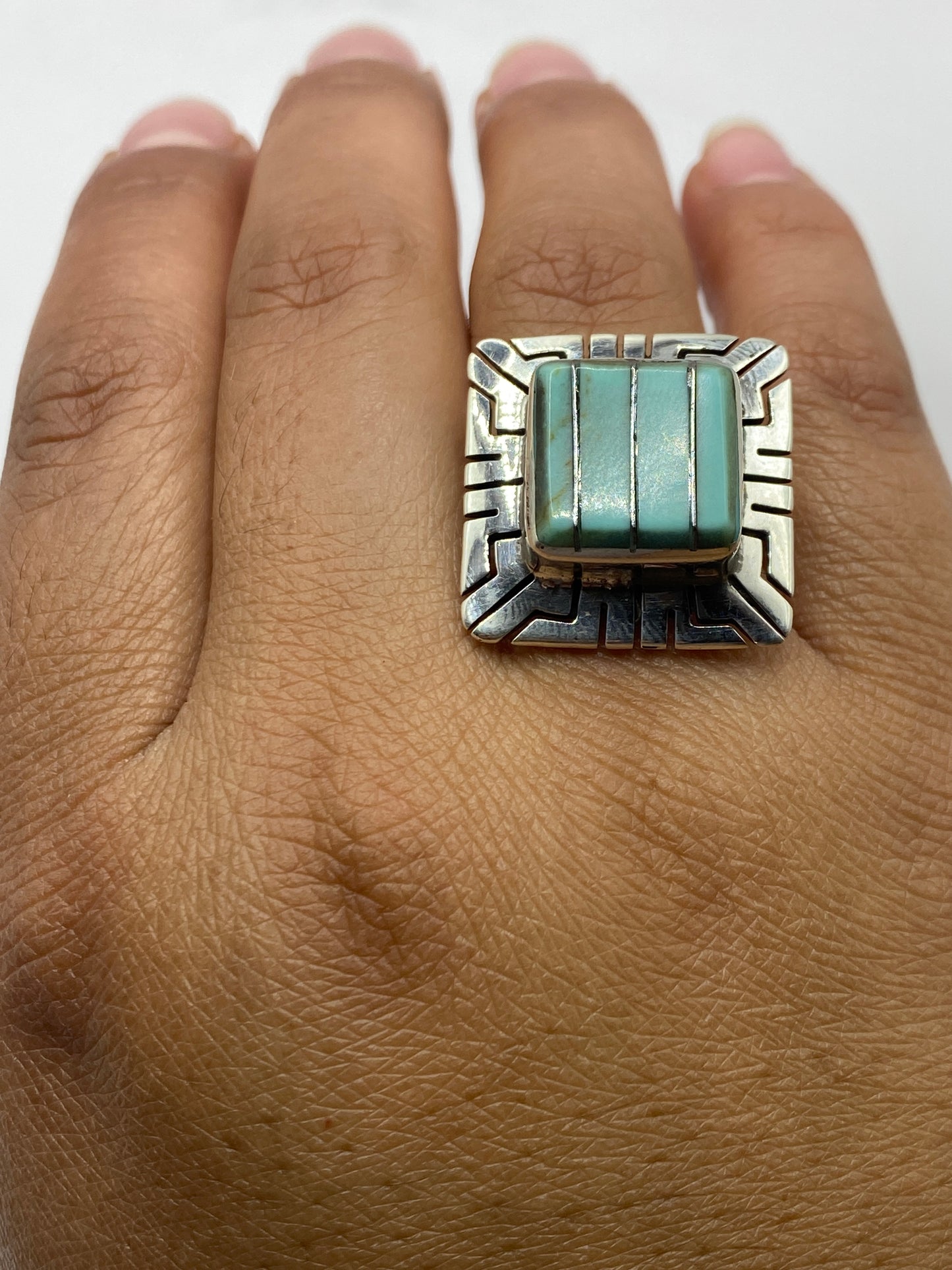 Anillo de turquesa en la mano de una mujer sobre fondo claro, mostrando talla y proporción