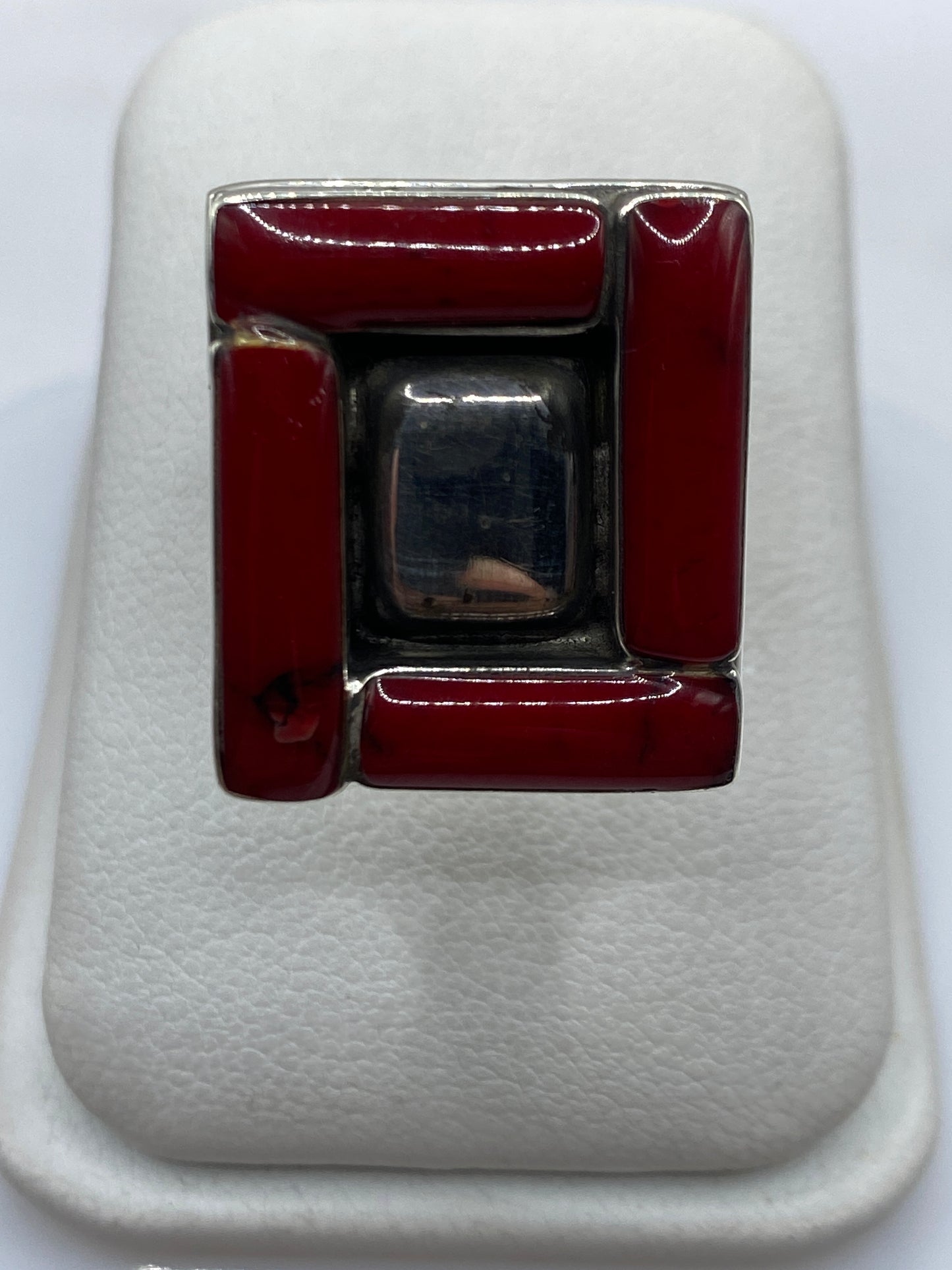 Anillo de plata con coral rojo en marco geométrico, vista frontal sobre fondo blanco