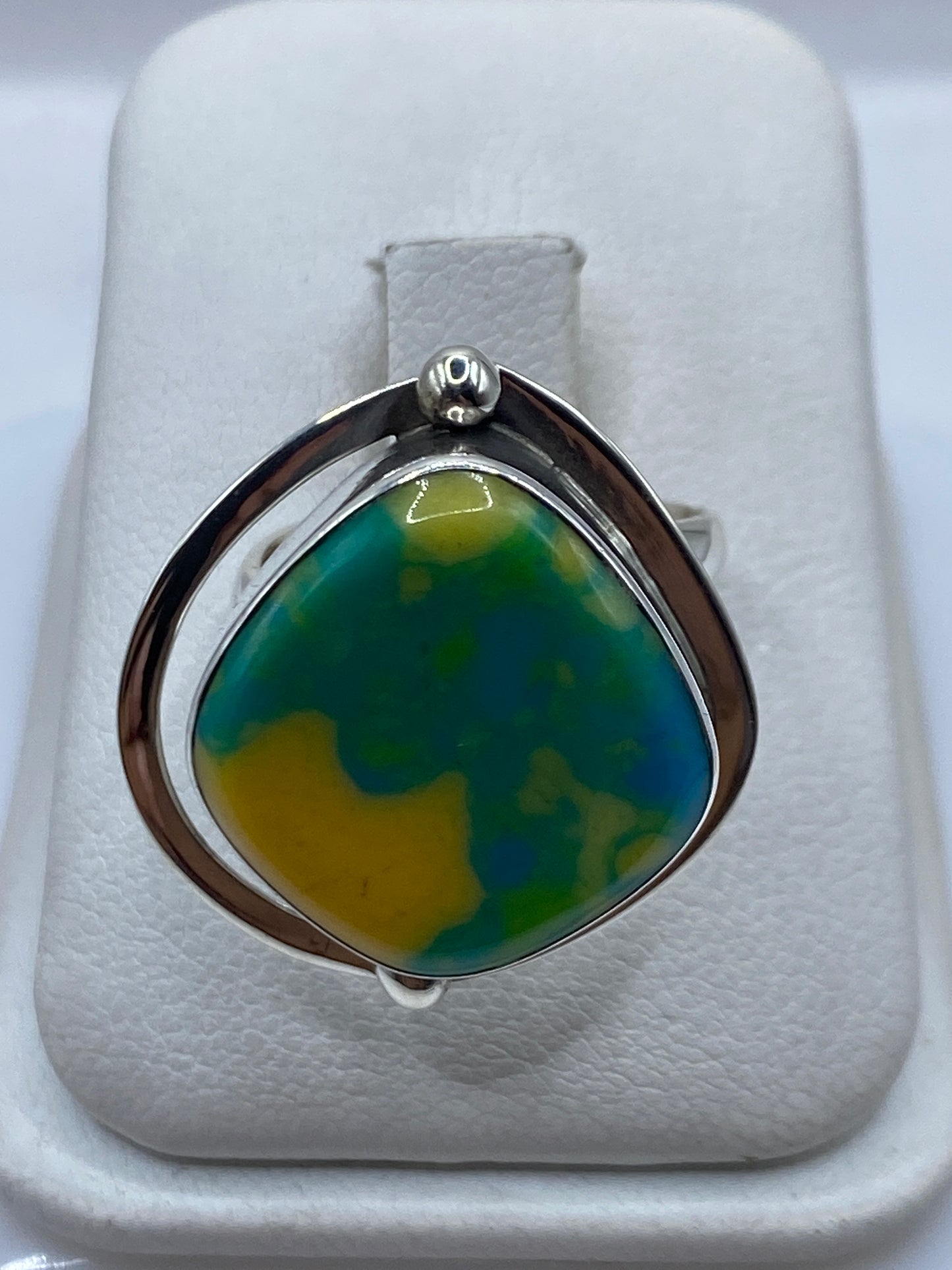 Anillo ajustable de plata con ópalo de fuego amarillo-verde-azul en la mano de una mujer