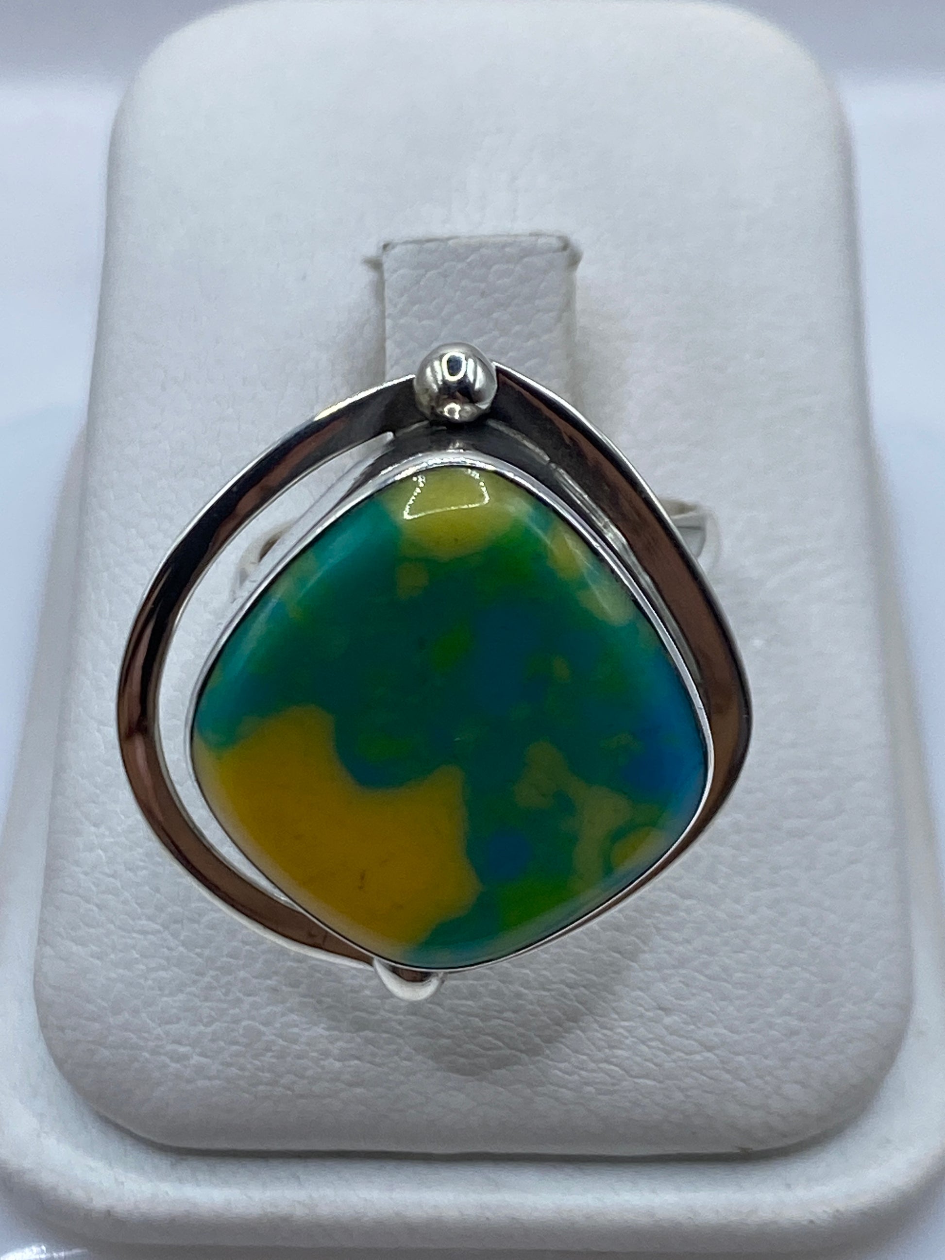 Anillo ajustable de plata con ópalo de fuego amarillo-verde-azul en la mano de una mujer