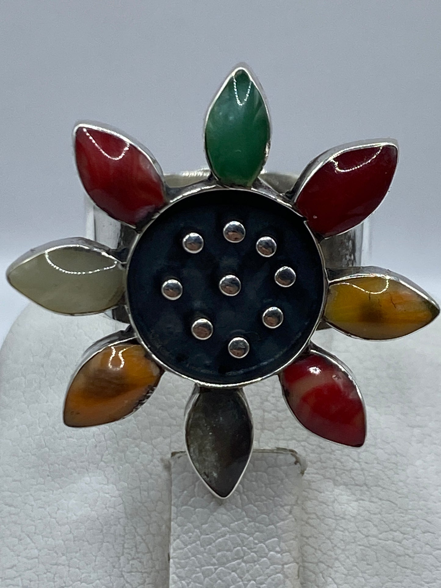 Anillo ajustable de plata en la mano mostrando los pétalos de colores naturales
