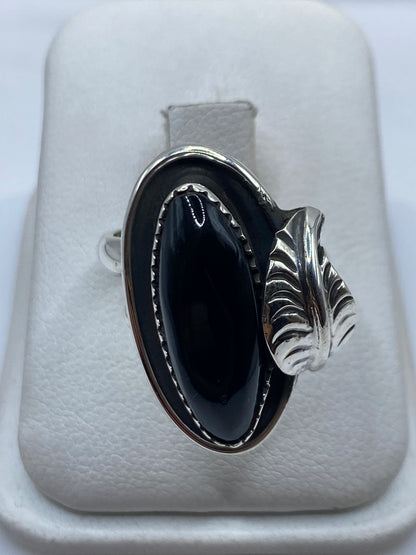 Anillo de plata ajustable con ónix negro oval pulido en la mano de una mujer