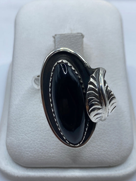 Anillo de plata ajustable con ónix negro oval pulido en la mano de una mujer