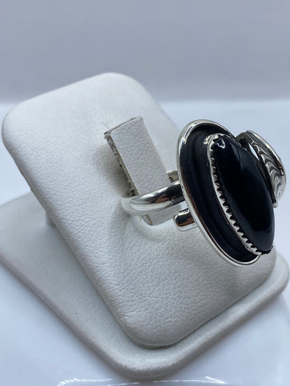 Vista frontal del anillo escultural con ónix negro y detalles grabados en plata