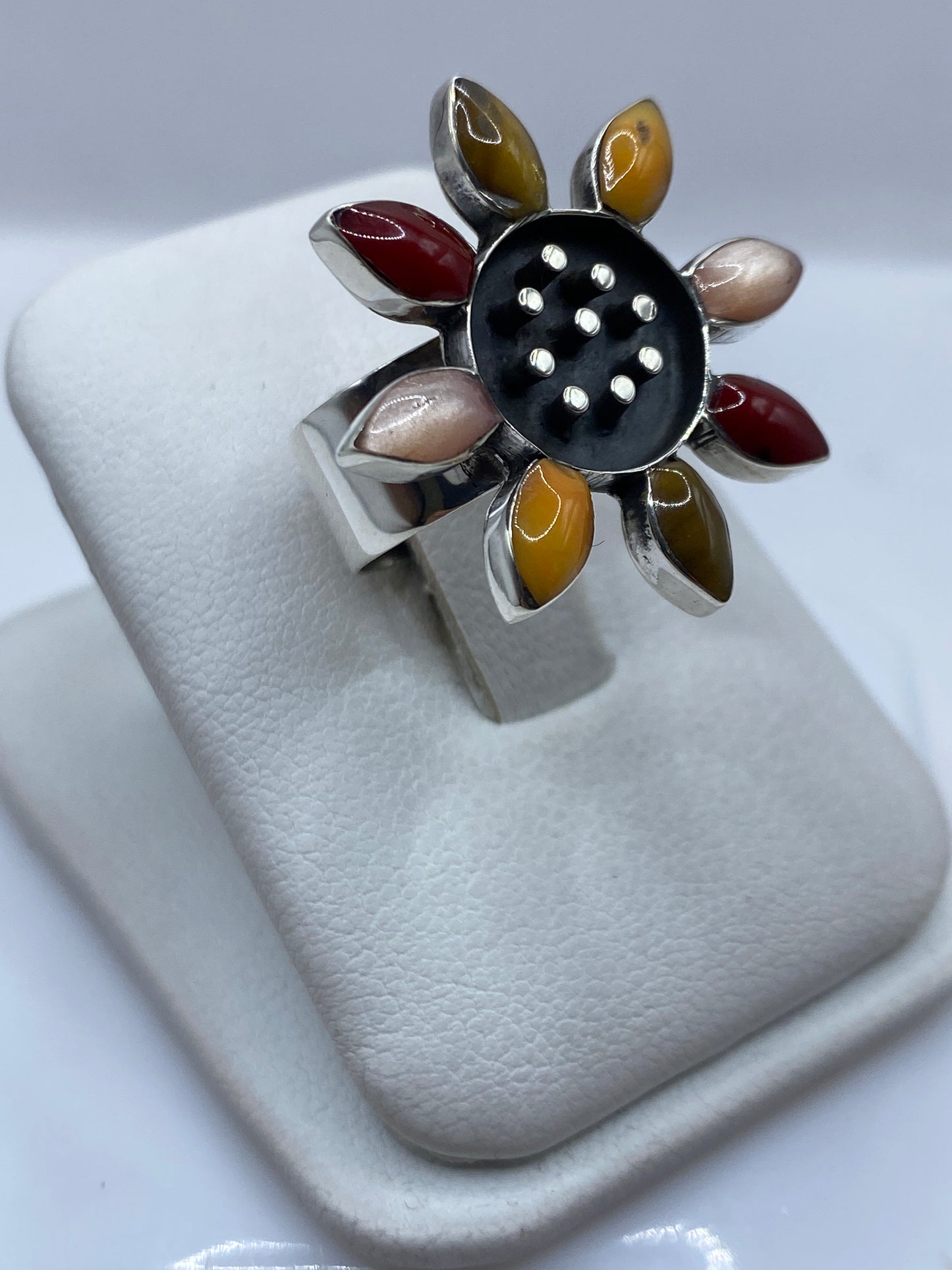 Detalle frontal del anillo mostrando el centro de onix negro y los pétalos de granate, ámbar y malaquita