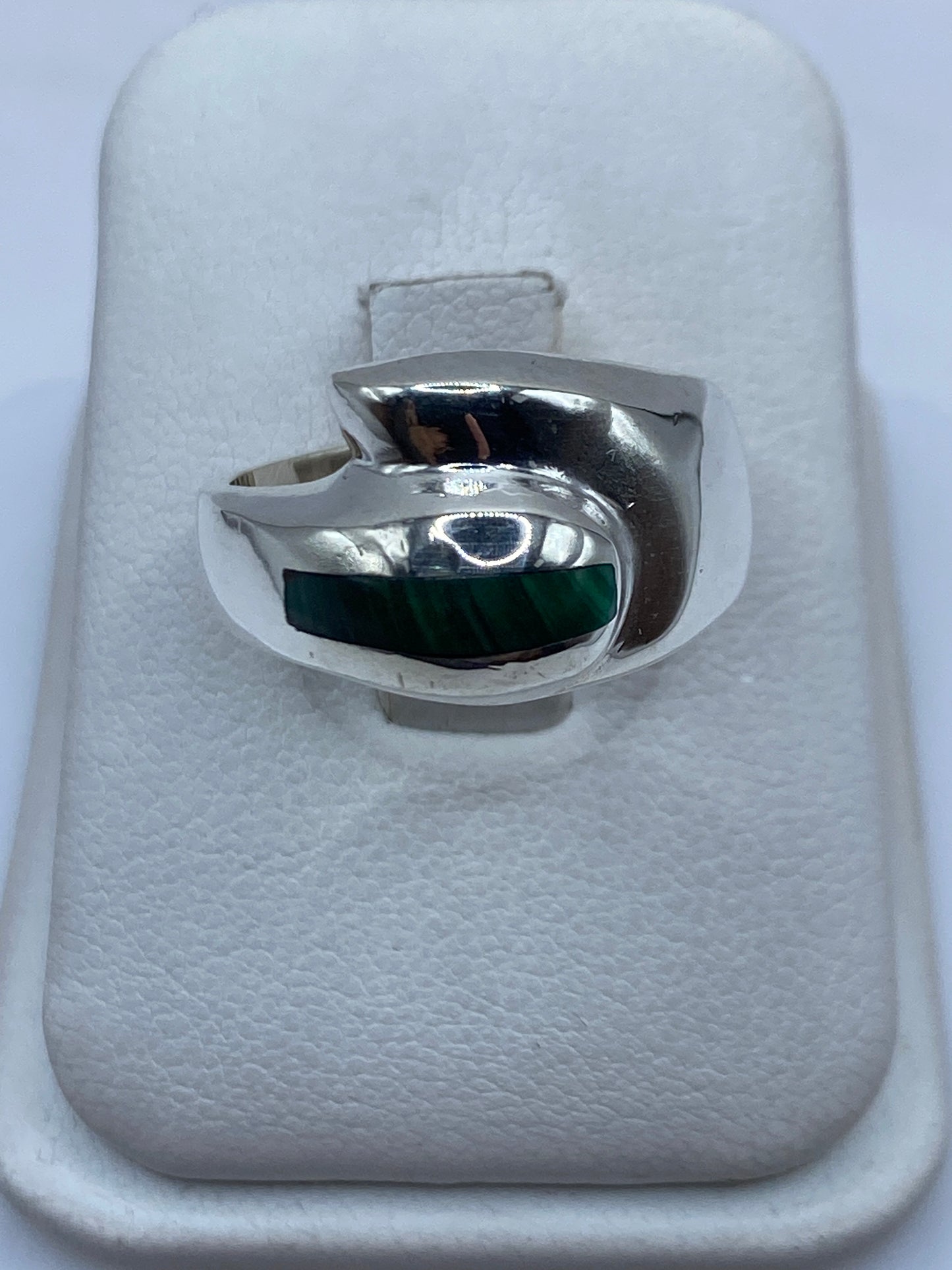 Anillo de plata con malaquita verde oscuro en la mano de un hombre, vista frontal