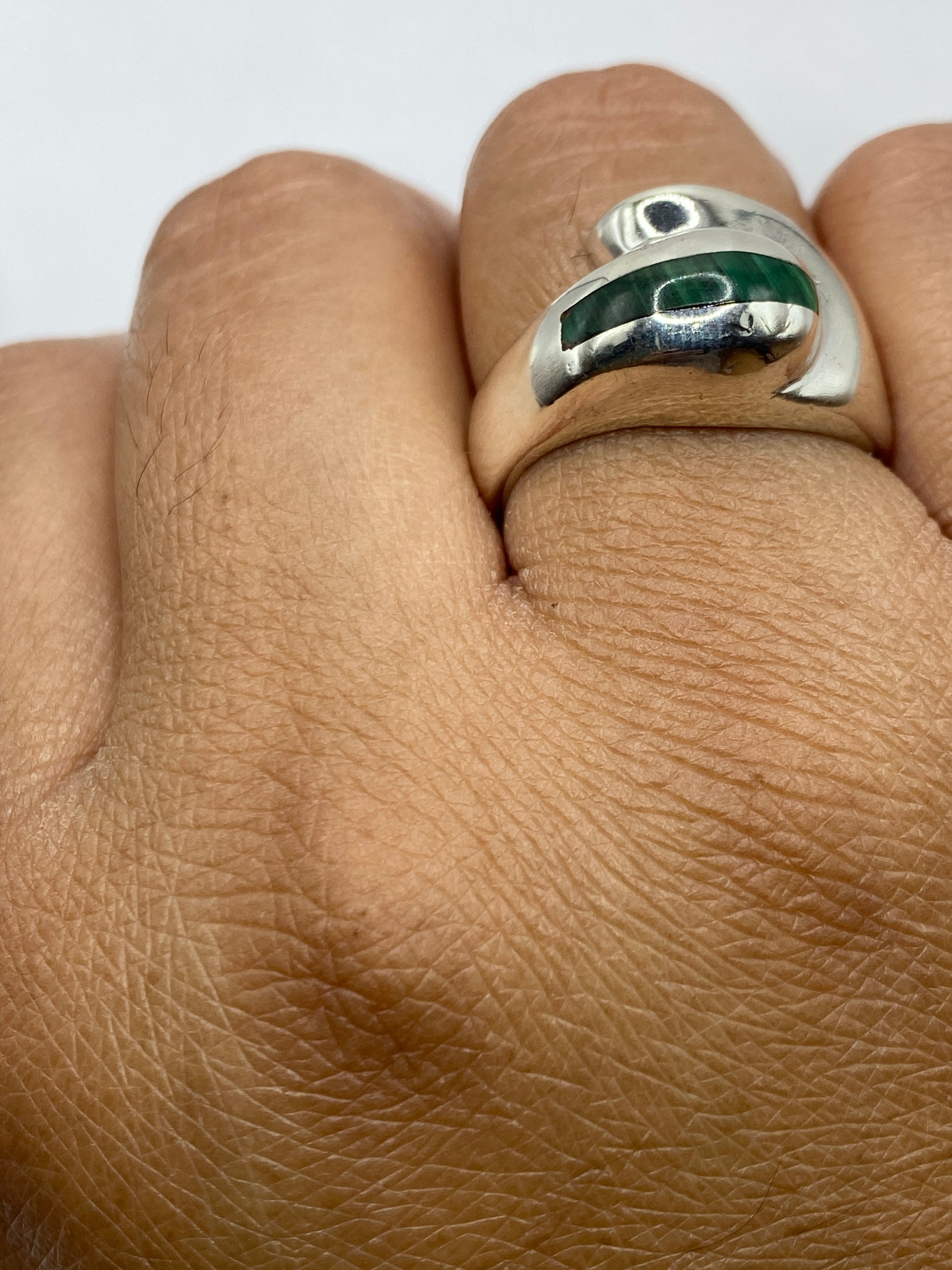 Anillo de malaquita y plata sobre fondo gris, mostrando los patrones naturales de la piedra