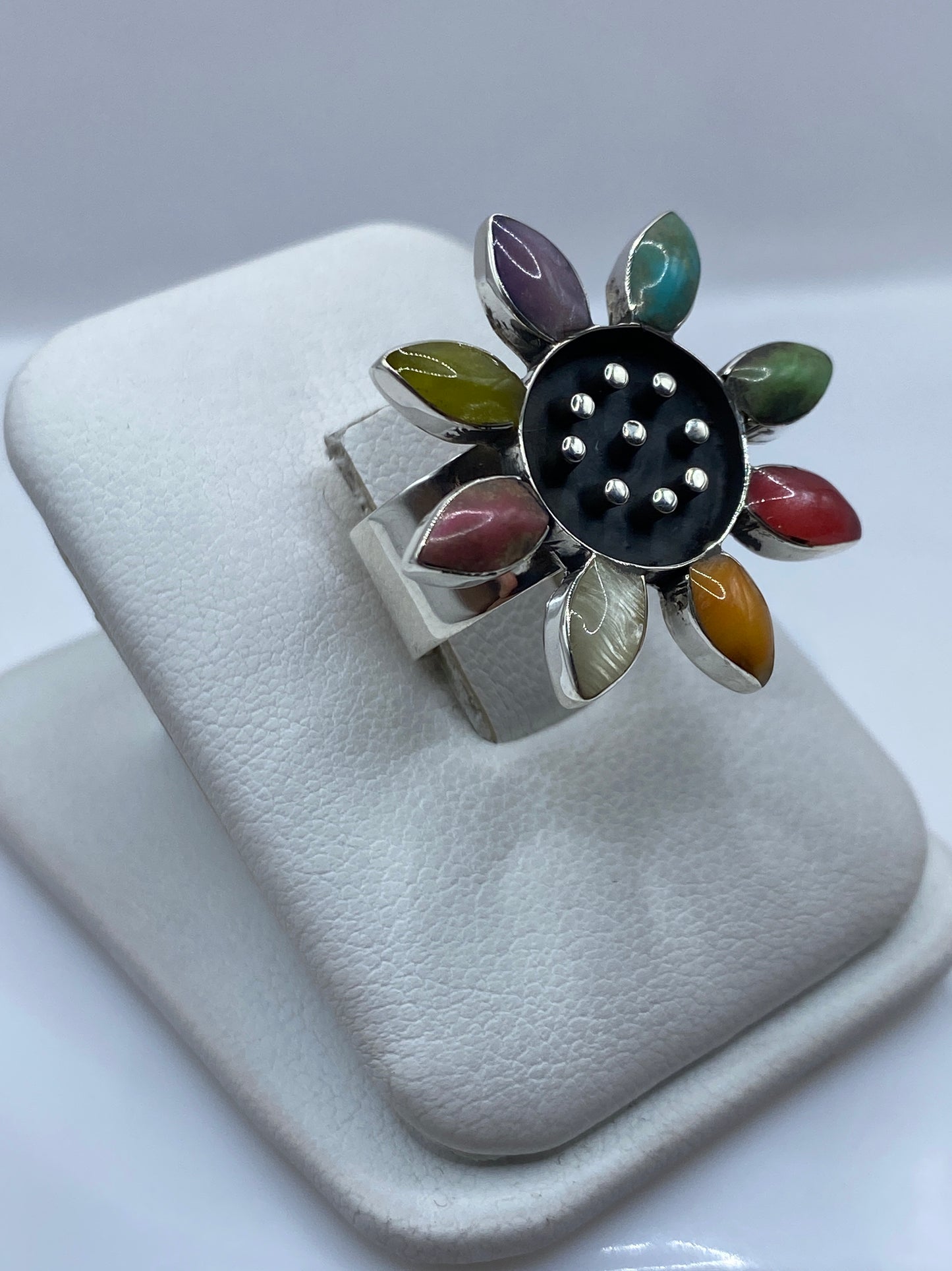 Vista superior del anillo de plata con pétalos de piedra roja, púrpura, verde y ámbar