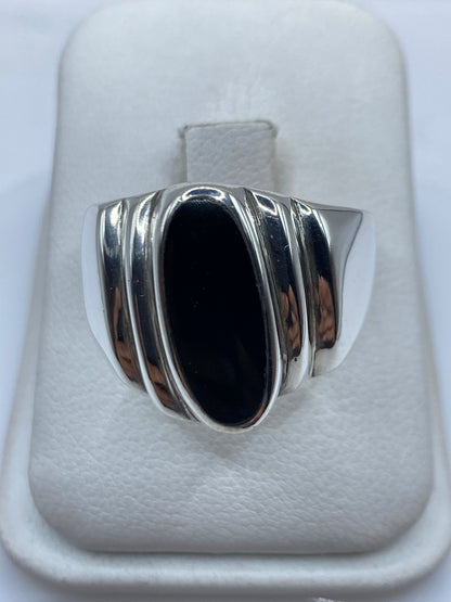 Anillo de plata con ónix negro oval en la mano de un hombre