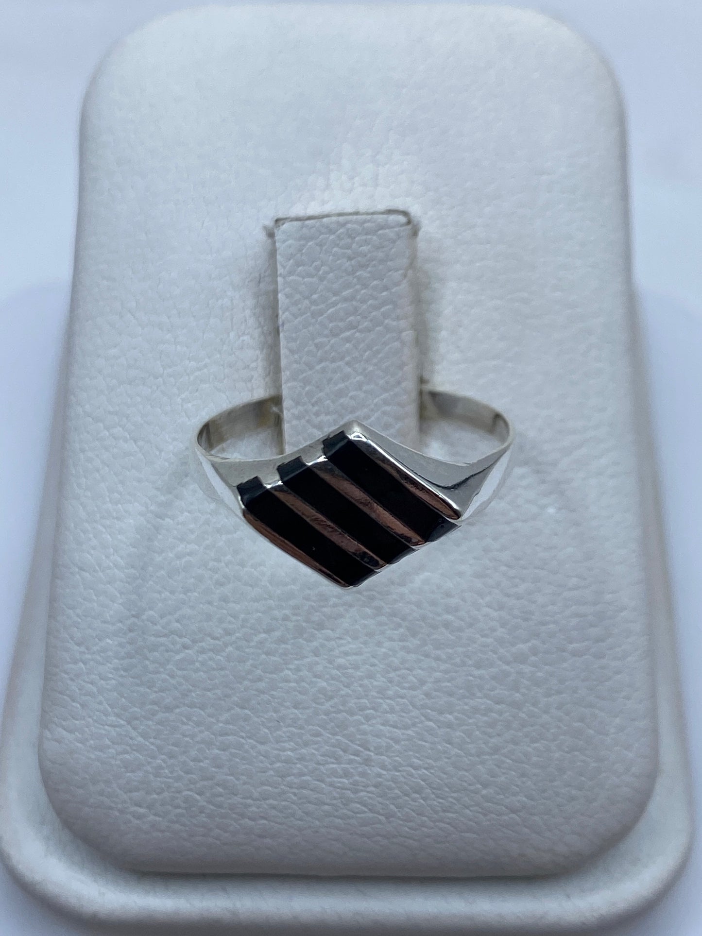 Anillo de plata con ónix negro en la mano de una mujer, vista frontal del solitario minimalista