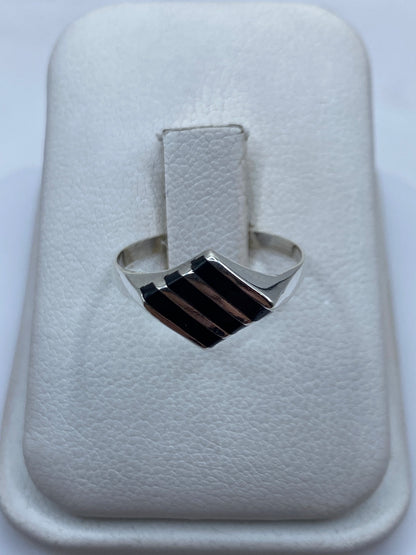 Anillo de plata con ónix negro en la mano de una mujer, vista frontal del solitario minimalista