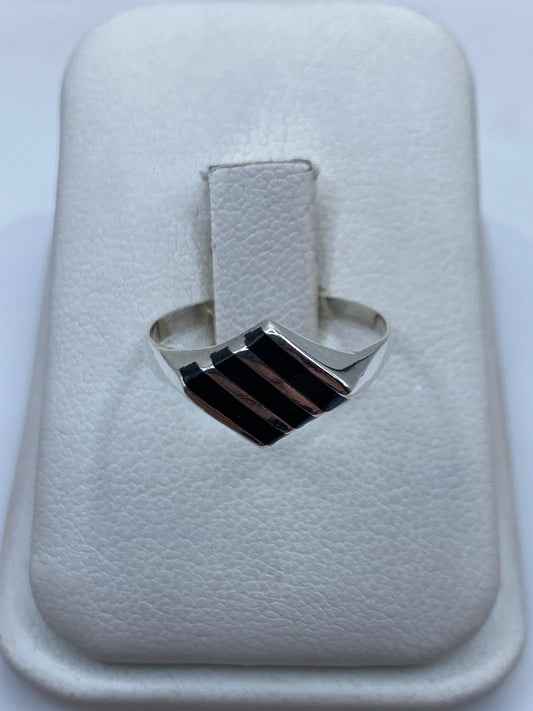 Anillo de plata con ónix negro en la mano de una mujer, vista frontal del solitario minimalista