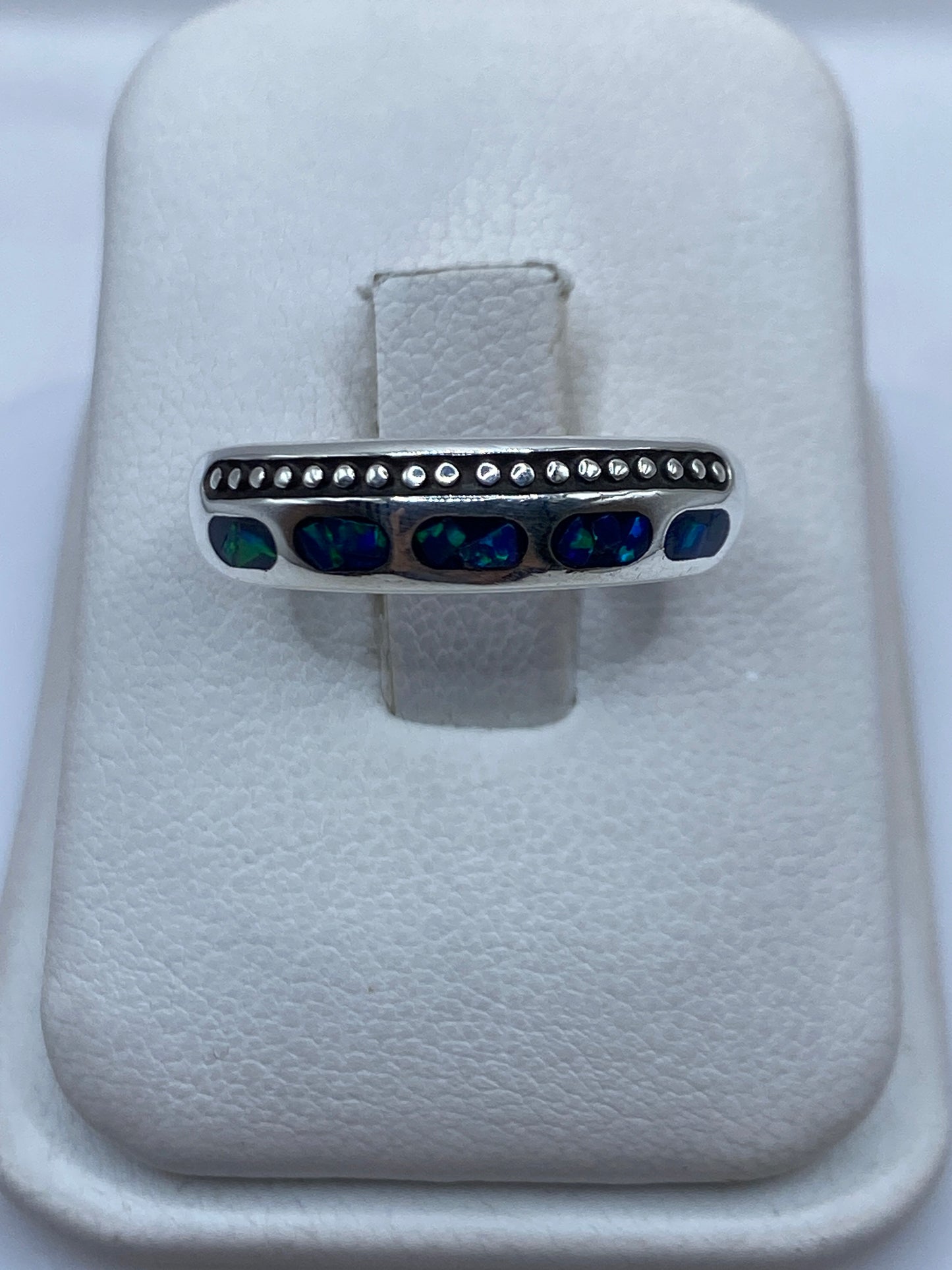 Anillo de plata .950 con ópalo de fuego azul en banda minimalista sobre fondo blanco