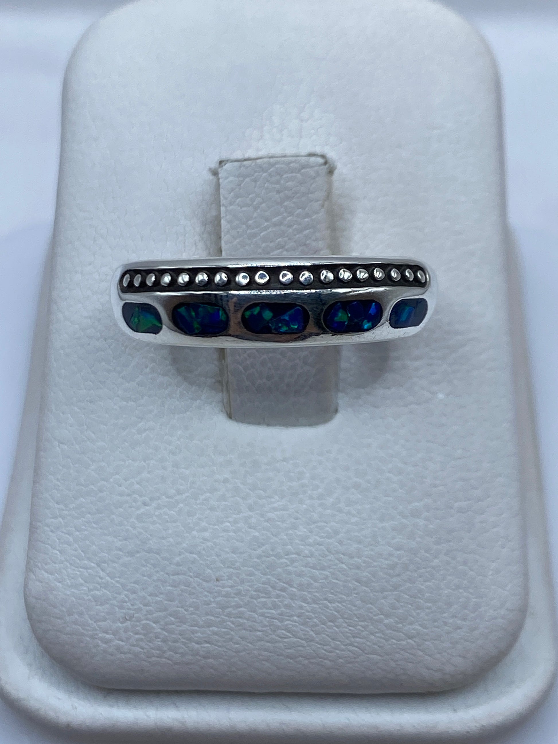 Anillo de plata .950 con ópalo de fuego azul en banda minimalista sobre fondo blanco