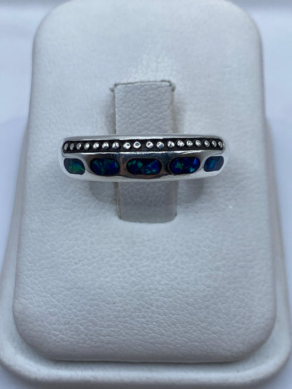 Anillo de plata .950 con ópalo de fuego azul en banda minimalista sobre fondo blanco