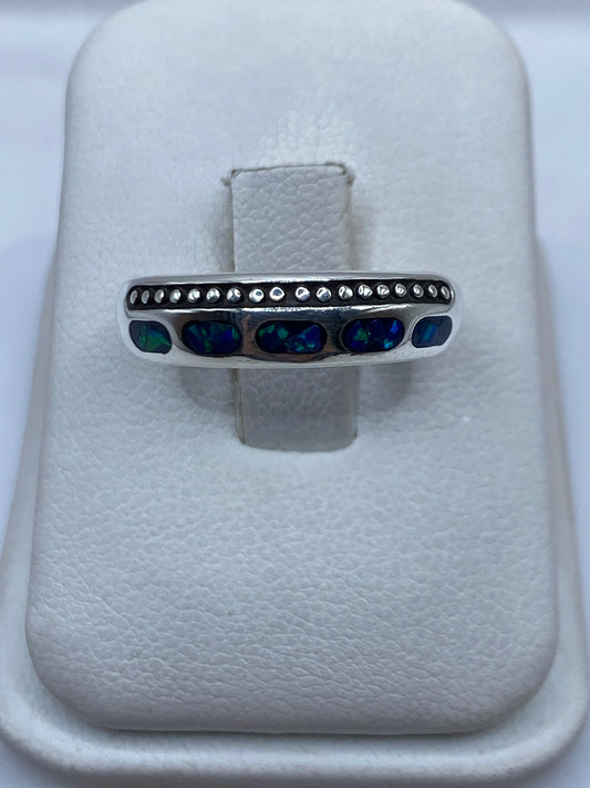 Anillo de plata .950 con ópalo de fuego azul en banda minimalista sobre fondo blanco