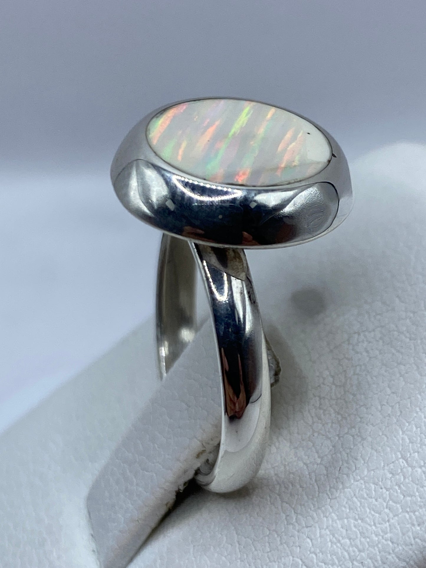 Detalle del ópalo de fuego natural en el anillo mostrando patrón iridiscente único