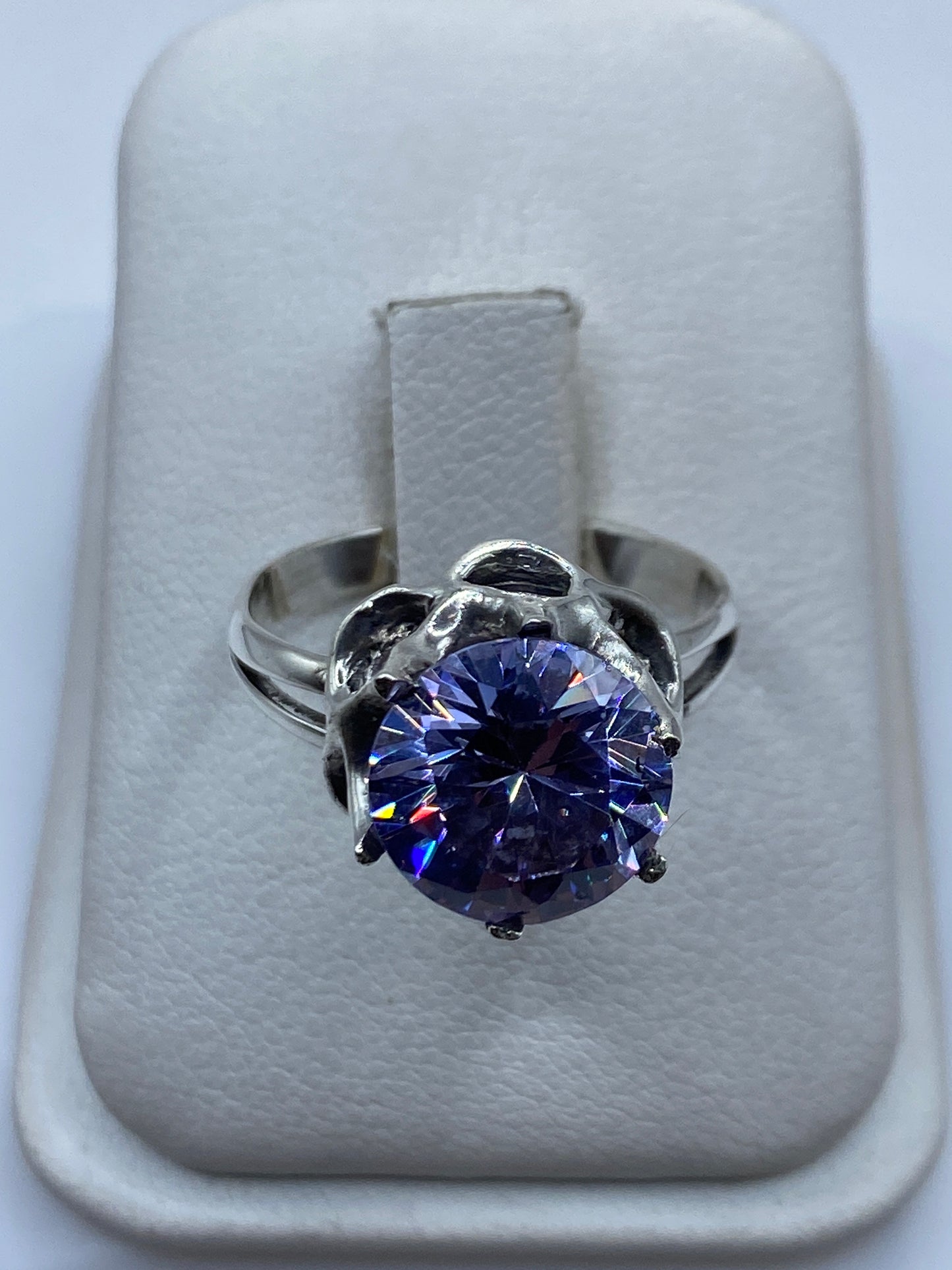 Anillo solitario de plata con circonia morada brillante sobre fondo blanco