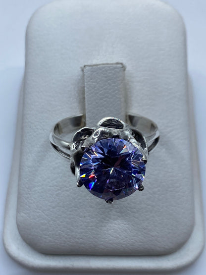 Anillo solitario de plata con circonia morada brillante sobre fondo blanco