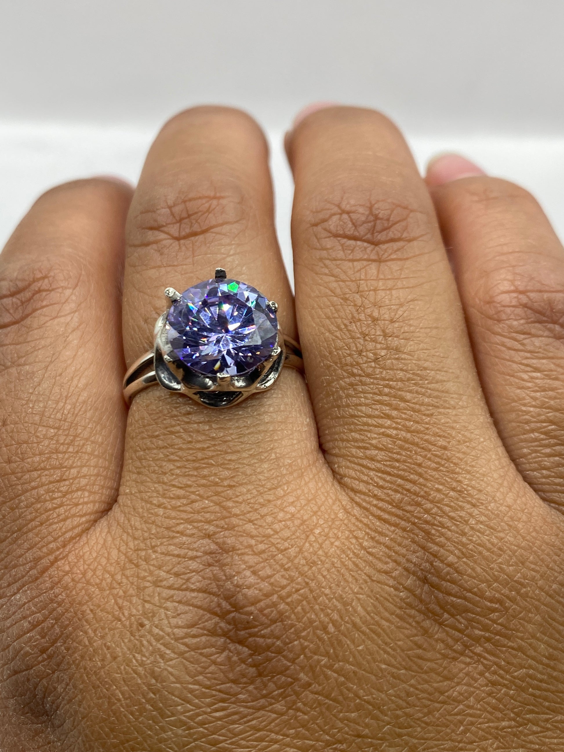 Anillo solitario en mano mostrando el sello 925 y la presencia del diseño