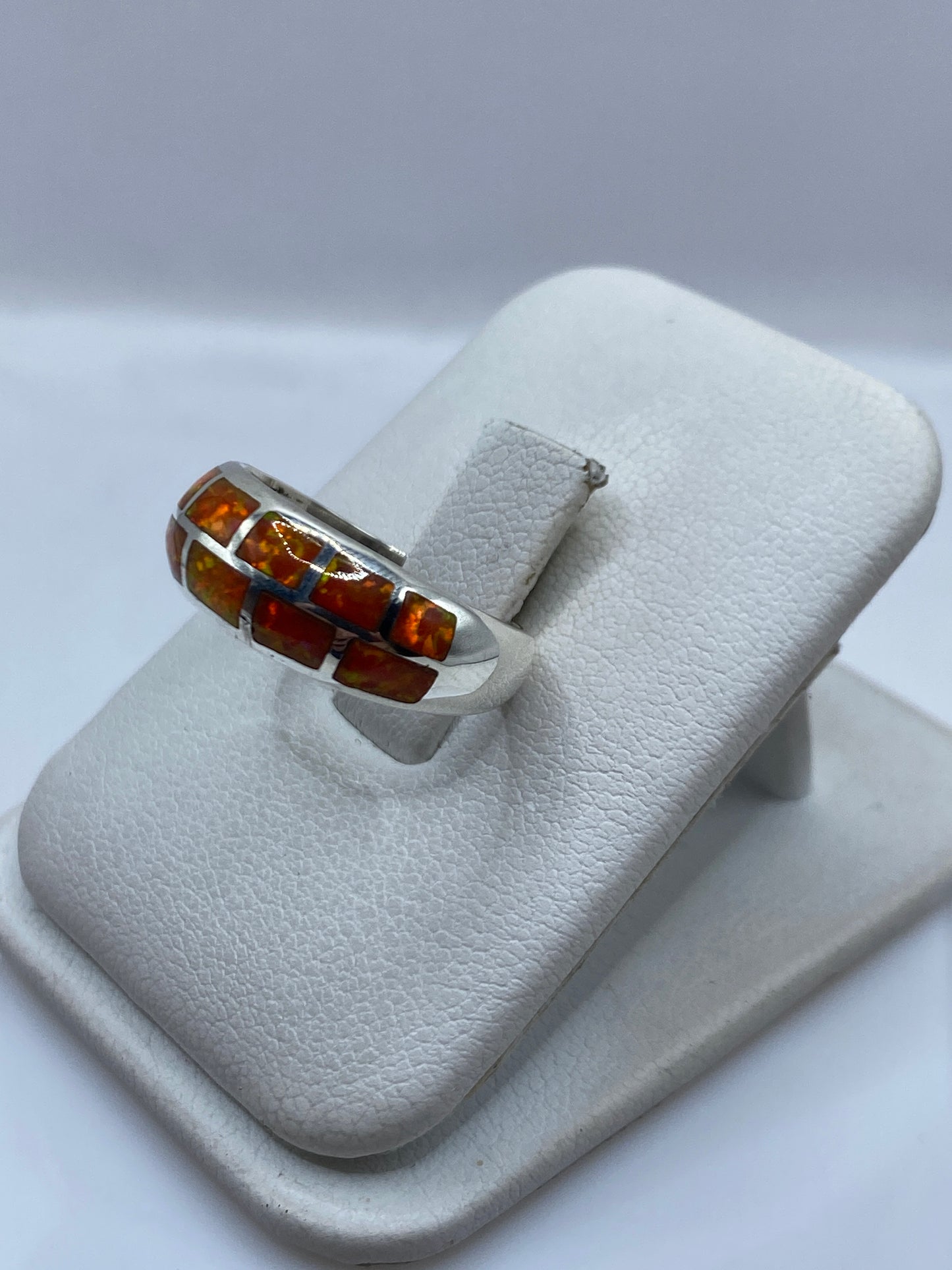 Vista de perfil del anillo unisex mostrando el juego de color naranja y rojo del ópalo