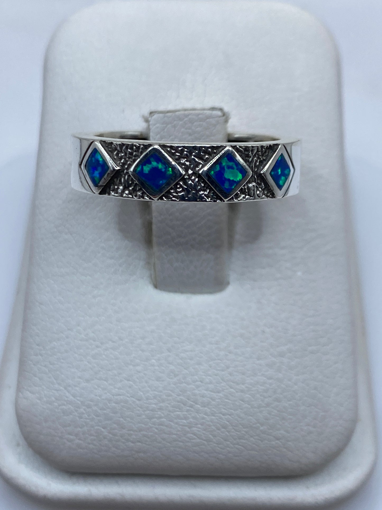 Anillo de plata .950 con ópalo de fuego azul en estuche blanco mostrando la banda texturizada
