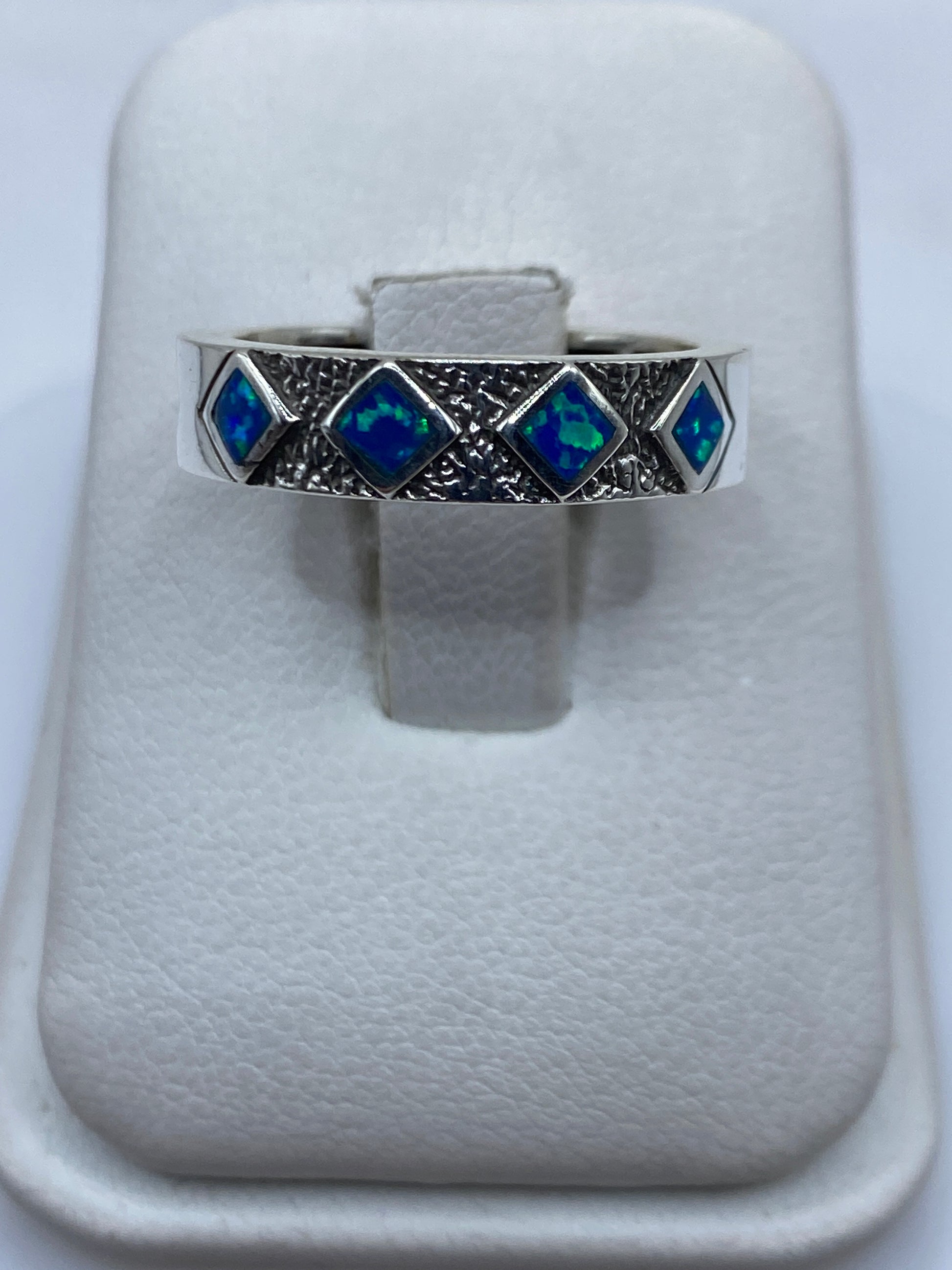 Anillo de plata .950 con ópalo de fuego azul en estuche blanco mostrando la banda texturizada