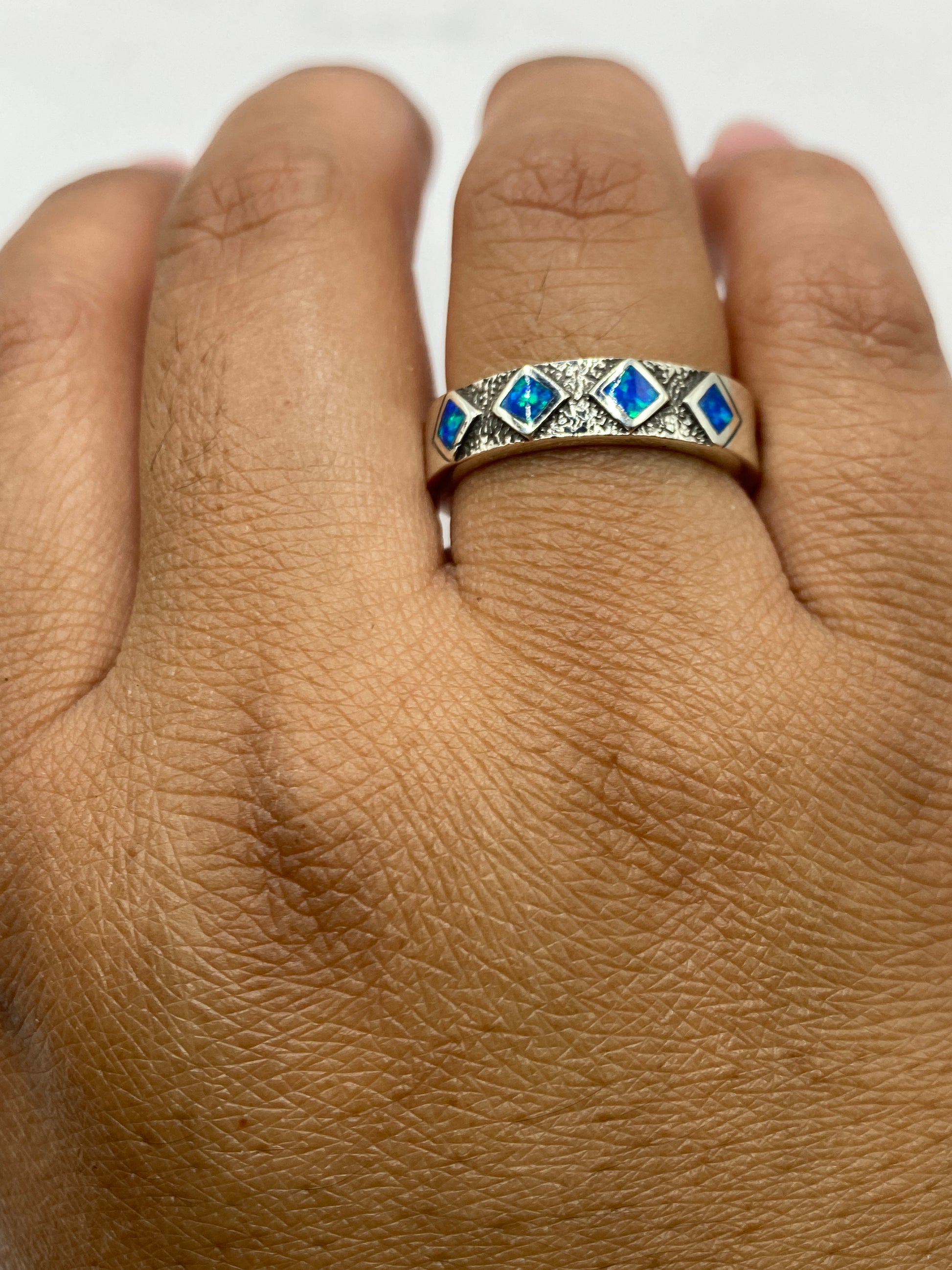Anillo en dedo mostrando el color azul vibrante del ópalo de fuego natural