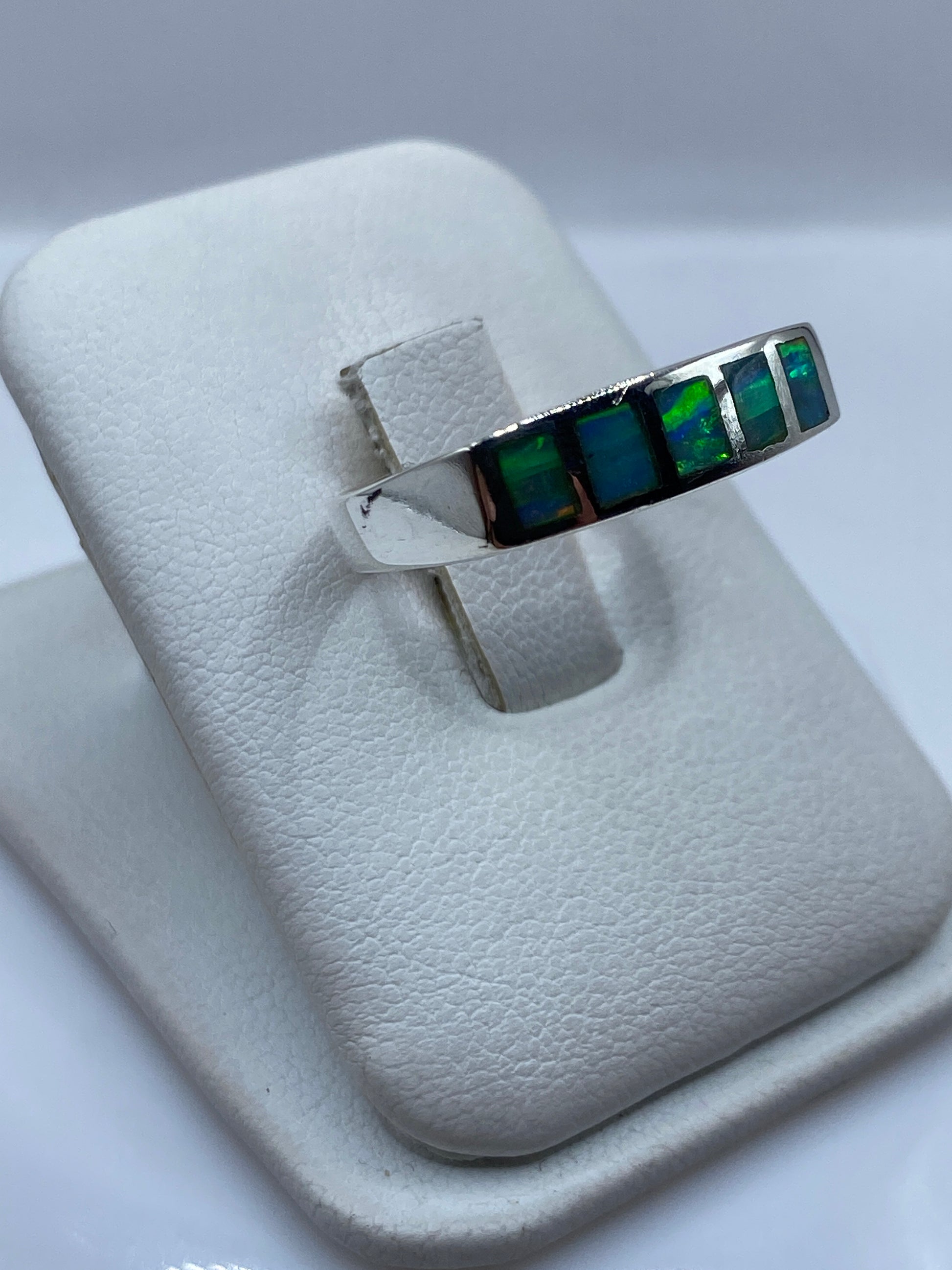 Vista lateral del anillo unisex mostrando el juego de color azul a verde del ópalo