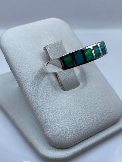 Vista lateral del anillo unisex mostrando el juego de color azul a verde del ópalo