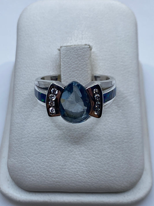 Anillo de plata .925 con ópalo de fuego azul en facetas, ancho de banda 4 mm, sobre fondo blanco