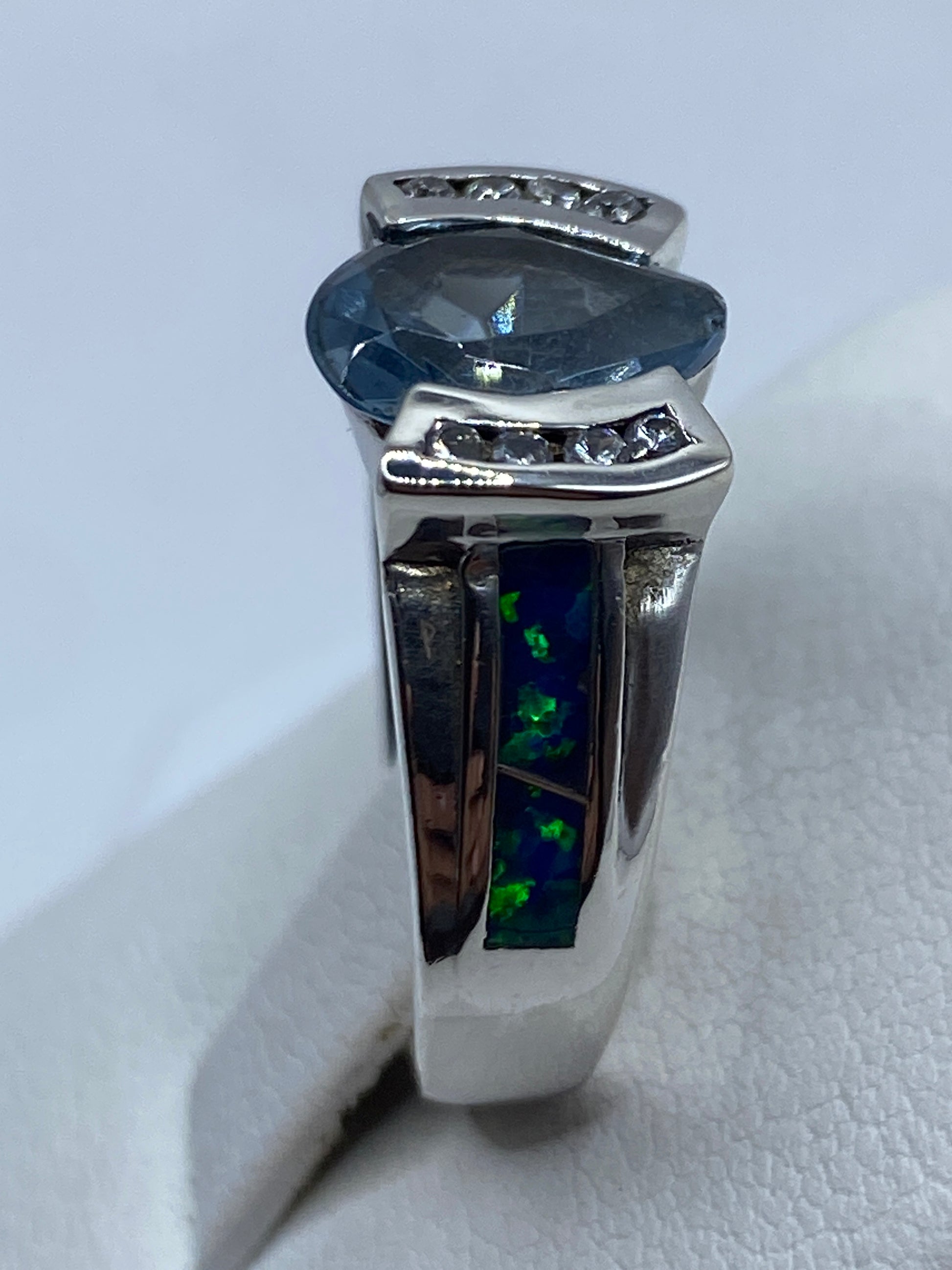 Anillo solitario de ópalo azul colocado en mano, vista lateral donde se ve la profundidad del engaste