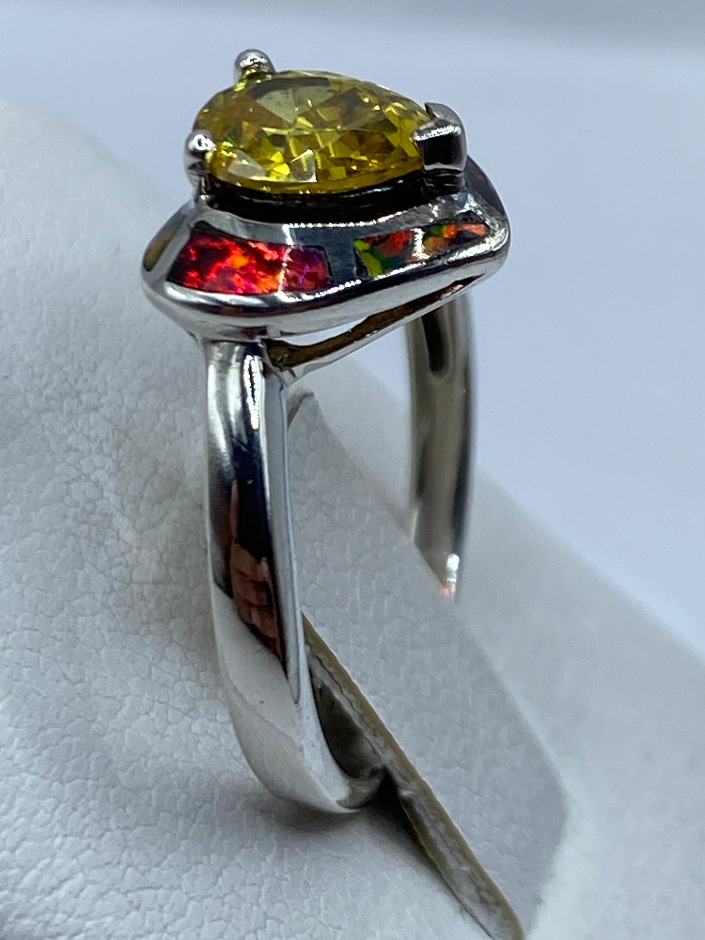 Anillo corazón ópalo de fuego puesto en mano de mujer mostrando los colores rojos y naranjas