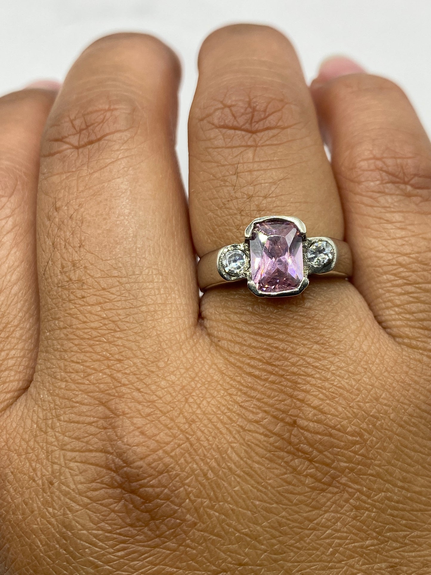 Anillo en mano de mujer, circonia rosa reflejando luz, diseño elegante y minimalista