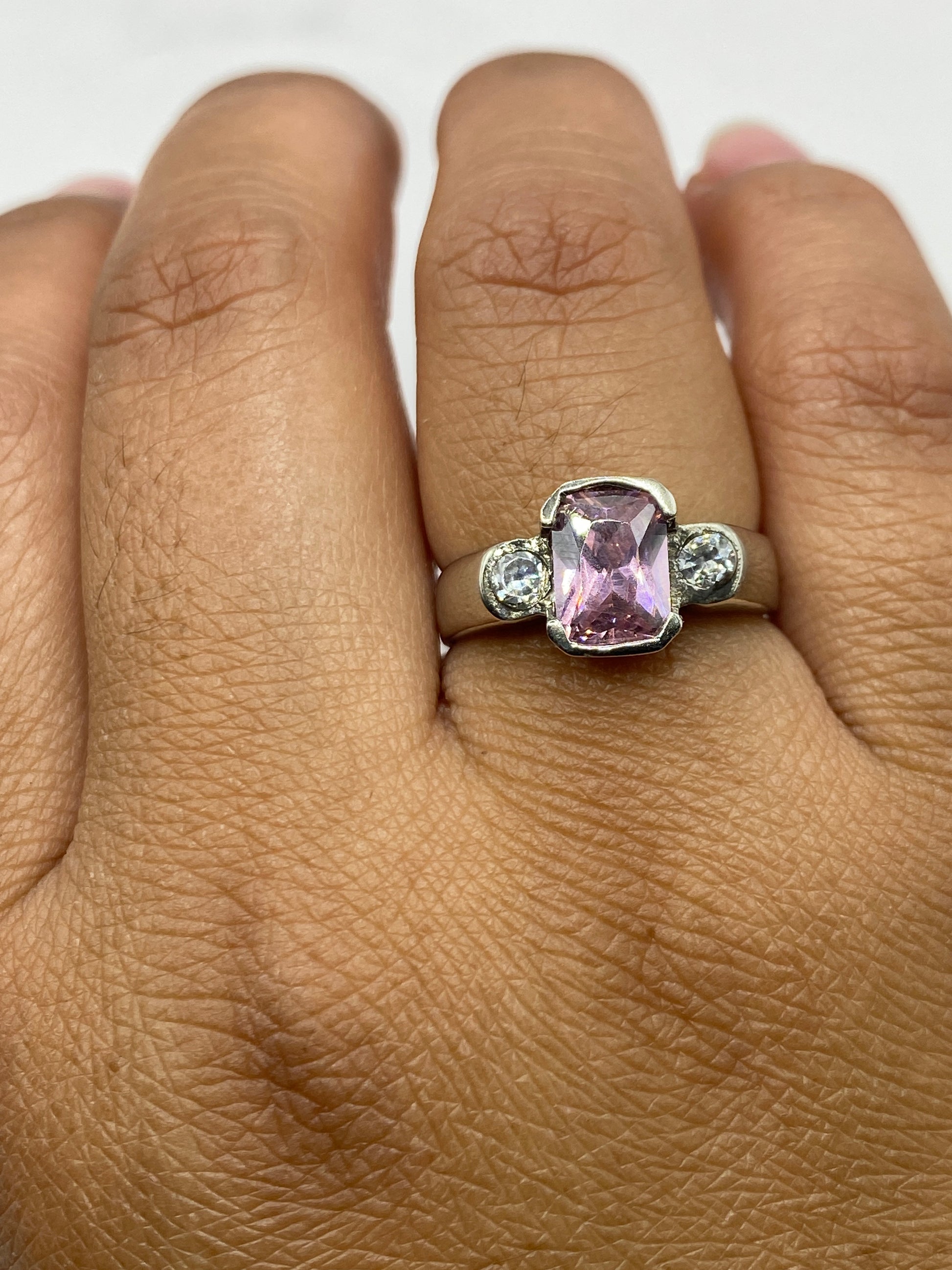 Anillo en mano de mujer, circonia rosa reflejando luz, diseño elegante y minimalista