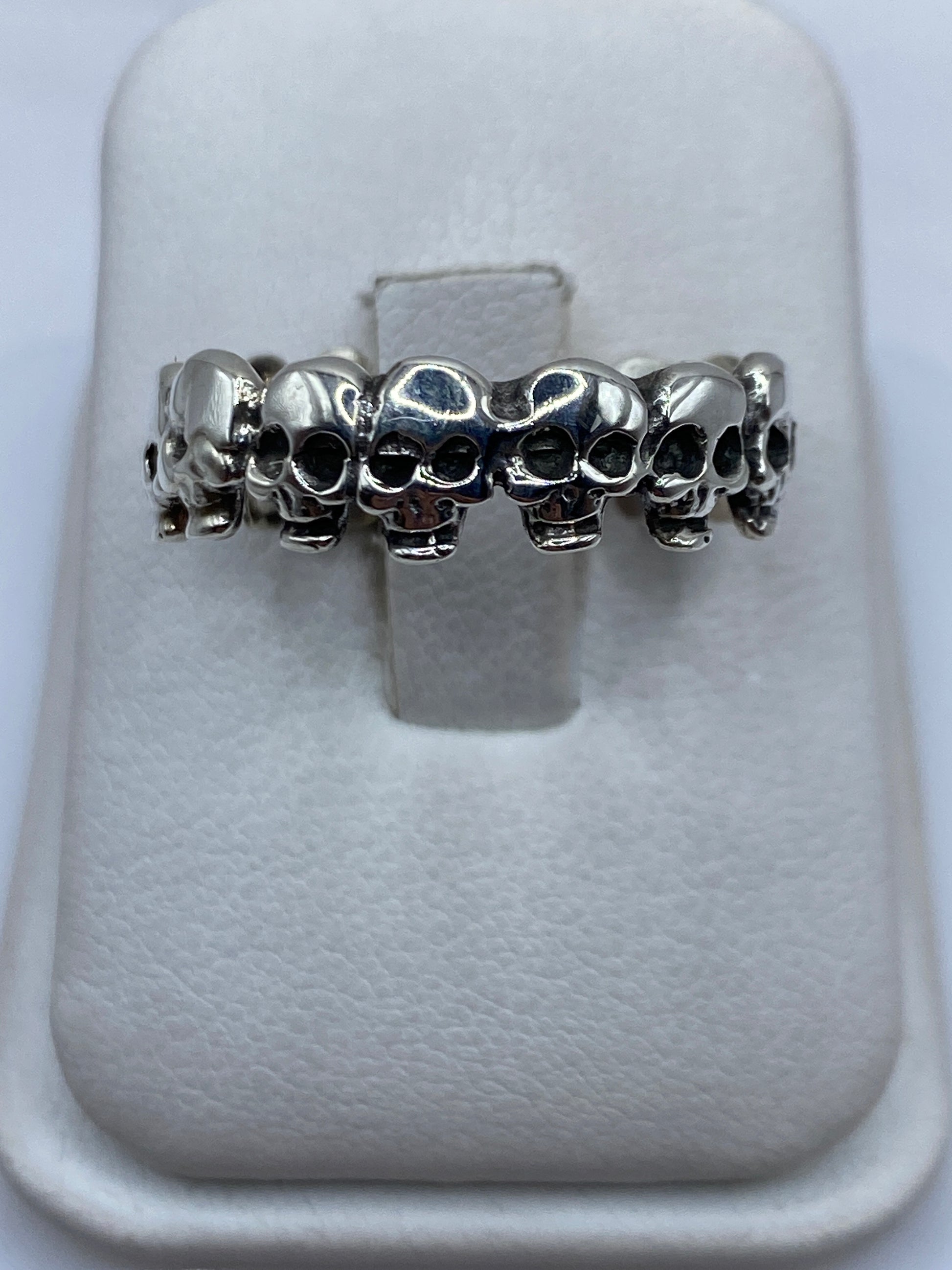 Anillo de plata con calaveras en relieve continuo en dedo de hombre