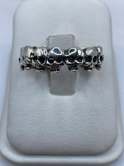 Anillo de plata con calaveras en relieve continuo en dedo de hombre