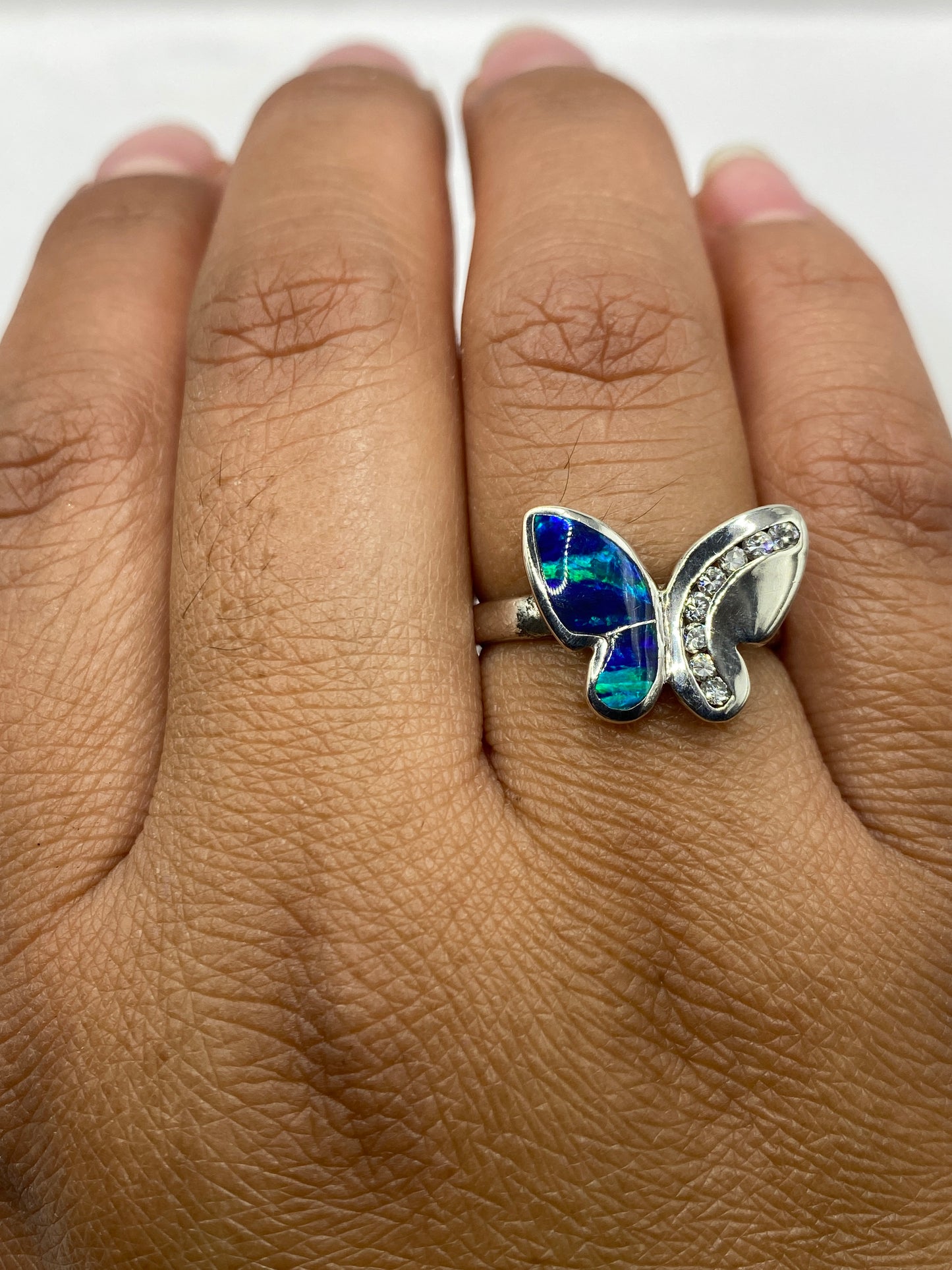 Anillo mariposa en dedo mostrando el brillo y cambio de color del ópalo