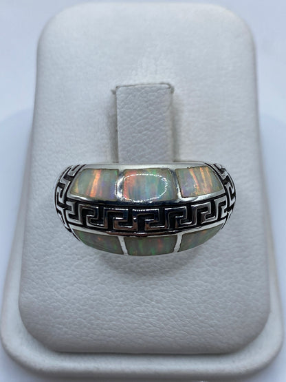 Anillo de plata .950 con ópalo de fuego natural en tono verde y naranja, sostenido en mano